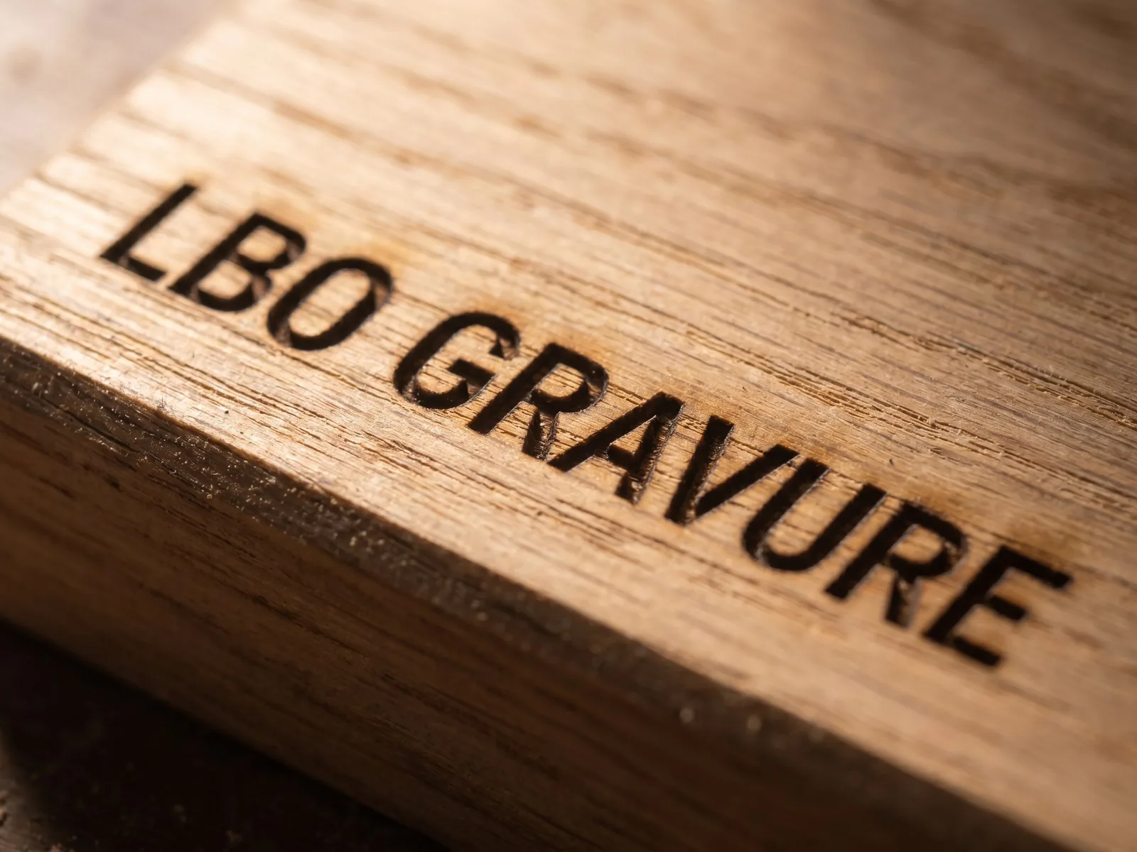 Gros plan macro de la gravure « LBO GRAVURE » dans du chêne